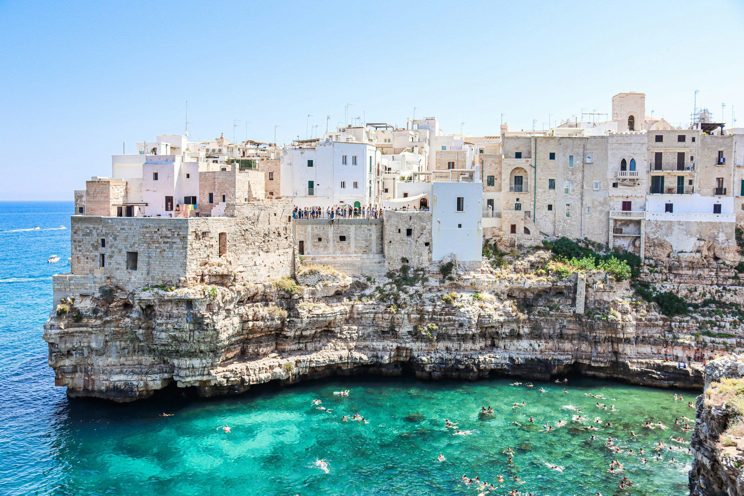 The white old town of Polignano a Mare on its cliff above clear swimming water